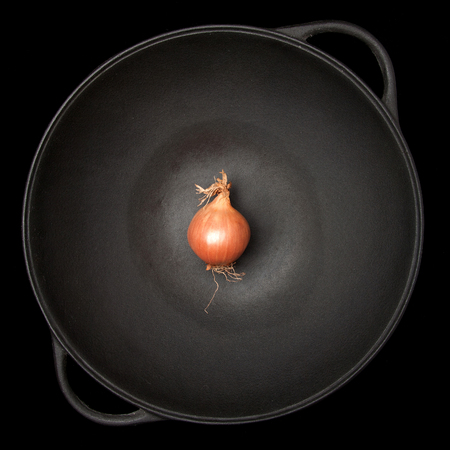 red onion in a wok on black backgroundの写真素材
