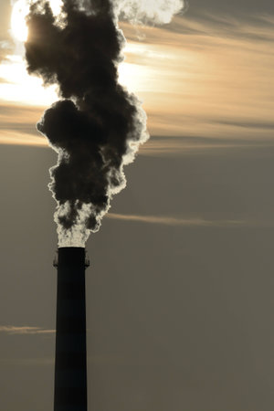 chimney pollutes the air and obscures the sunの写真素材