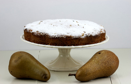 Italian cake with ricotta, pears and drops of chocolate on white and wooden table.の写真素材