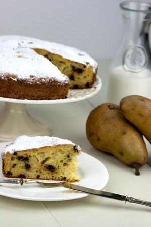 Italian cake with ricotta, pears and drops of chocolate on white and wooden table.の写真素材