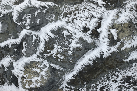 Snow and ice on a stone wall at winter