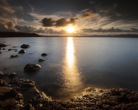 Big Torch: harsh bath of light for the rocks on the shore before the golden hours. Lake di Bracciano, Province of Rome, Lazio, Italy, Europe.の写真素材