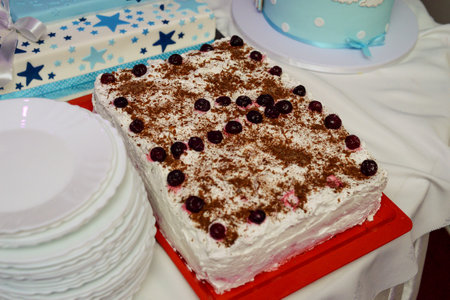 Square chocolate cake decorated with cherries and crumbled chocolate