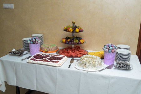 A sweet table ready to serve with ready cutlery, three cakes and a variety of healthy and delicious fruits.の写真素材