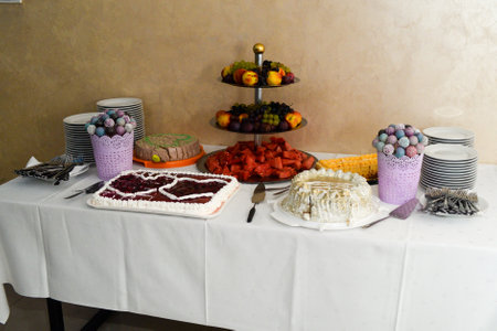 A sweet table ready to serve with ready cutlery, three cakes and a variety of healthy and delicious fruits.の写真素材