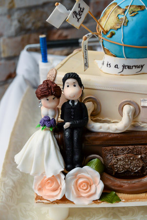 cake in the shape of two suitcases, on the top is a globe of the planet earth with the flags of the cities and on the bottom the newlywedsの写真素材
