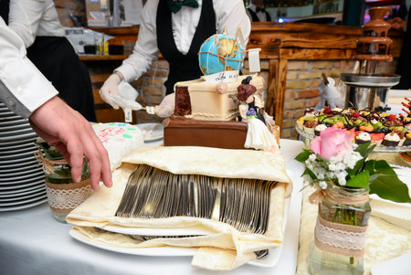 A serving table with a wedding cake, a chocolate fountain, fruit decorations and small cakes in various colors.の写真素材