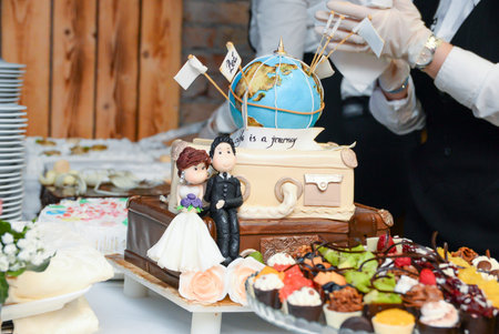 A serving table with a wedding cake, a chocolate fountain, fruit decorations and small cakes in various colors.の写真素材