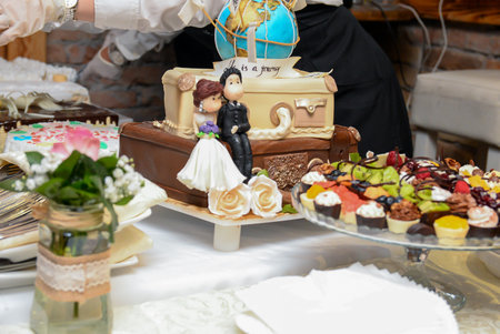 A serving table with a wedding cake, a chocolate fountain, fruit decorations and small cakes in various colors.の写真素材