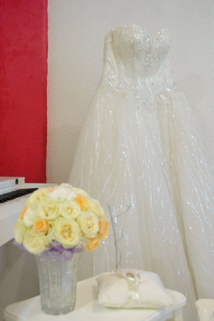 A white lace wedding dress in front of a white wall and in front of it is a bouquet of beautiful flowersの写真素材