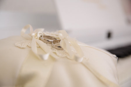Elegant white gold wedding rings on a light brown decorative cushionの写真素材