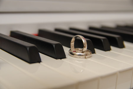 Two white gold wedding bands set on piano keysの写真素材