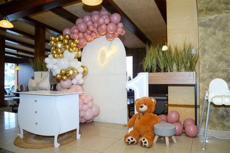 Various colorful balloons, neon number one, big brown bear and neon letters that say number one as a birthday decorationの写真素材