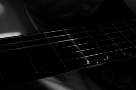 Close-up photo of an acoustic guitar with shadows. Guitar strings, neck, frets and bodyの写真素材