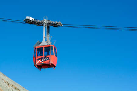 A red cable car on its way from Skalnate pleso to Lomnicky peak. Red gondola moving up to Lomnica...