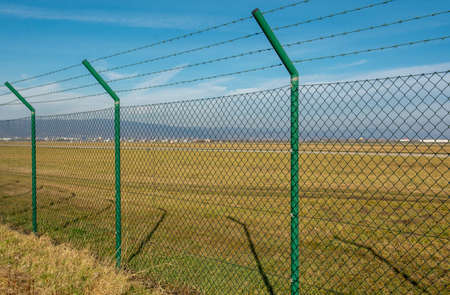 Green steel wire mesh fence around the airport area. Restricted area protection.の写真素材
