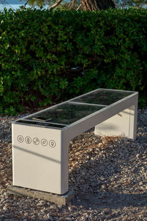 Smart Solar Bench in public place,  powered by sunlight provides wireless and wired charging for...
