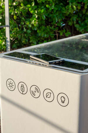 Smart Solar Bench in public place,  powered by sunlight provides wireless and wired charging for users, free wifi and temperature and weather sensors.の写真素材