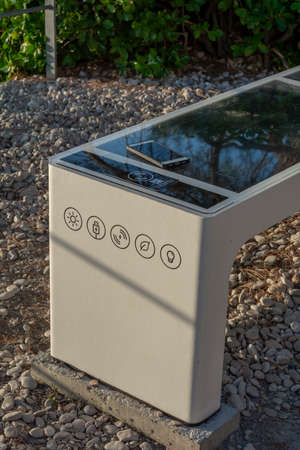 Smart Solar Bench in public place,  powered by sunlight provides wireless and wired charging for users, free wifi and temperature and weather sensors.の写真素材