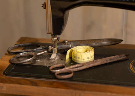 Old vintage sewing machine with an old rusty pair of scissors and a Tape Measure Sewing Tailor Cloth Ruler.の写真素材