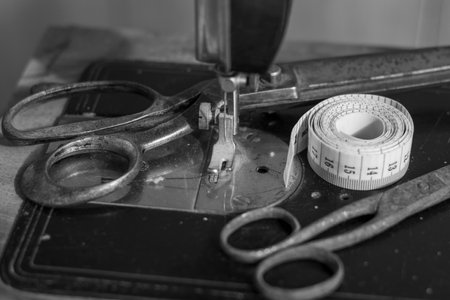 Old vintage sewing machine with an old rusty pair of scissors and a Tape Measure Sewing Tailor Cloth Ruler. Black and white photography.の写真素材