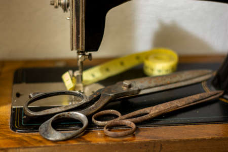 Old vintage sewing machine with an old rusty pair of scissors and a Tape Measure Sewing Tailor Cloth Ruler.の写真素材