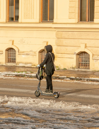 Unrecognizable person riding electric scooter on snowy road in the winter season.の写真素材