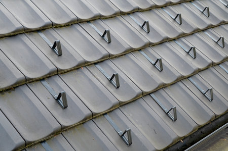 Snow guards, retainers  or snow hooks on the tile roof. Snow guards to keep snow from sliding off the roof too quickly.の写真素材