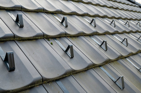 Snow guards, retainers  or snow hooks on the tile roof. Snow guards to keep snow from sliding off the roof too quickly.の写真素材