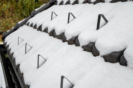 Snow guards, retainers  or snow hooks on the tile roof covered by snow in the winter time.の写真素材