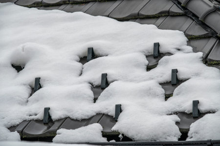 Snow guards, retainers  or snow hooks on the tile roof covered by snow in the winter time.
