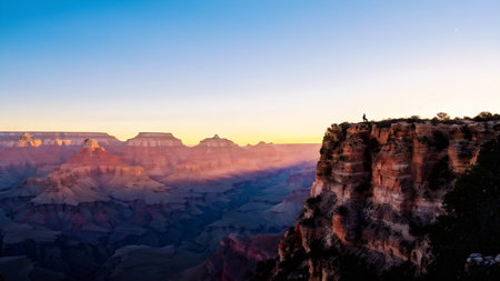 sunrise over grand canyon in vibrant colors casting light on overhanging rock formationsの素材