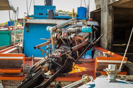 on an old boat you can see an old colorful motor that looks as if you had built it yourself because the ship's engine is visible from the outside without any claddingの写真素材