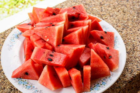 on the picture you can see a plate with cut watermelon pieces, the color of the fruit is bright red.の写真素材