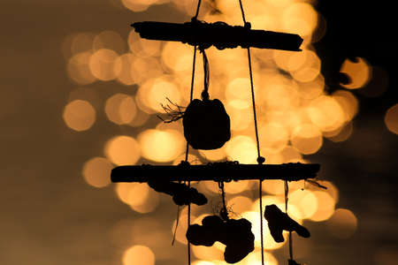 A wind chimes with shells by the sea at dusk, the background of the picture is completely blurred.の写真素材