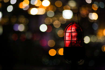on the picture you can see a red position light of a building and in the background the lights are blurredの写真素材