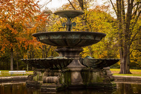 An old fountain with colorful autumn trees in the backgroundの写真素材