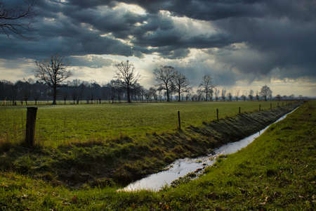 Dutch landscape with farmlands and heavy clouds during storm