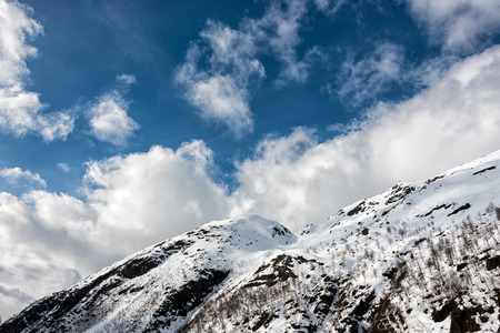 Snowcaped Mountain under blue sky with white puffyesの写真素材