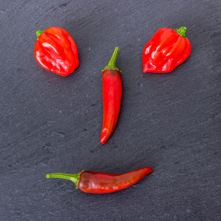 different varieties of chilli form a faceの写真素材