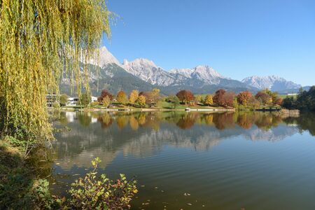 View of Lake Ritzensee on a sunny autumn day in Saalfelden with reflection of the Steinernes Meer. Saalfelden, Pinzgau, Salzburg Land, Austria, Europe.の写真素材