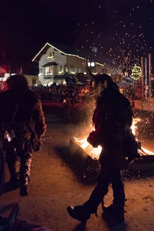 Kaprun, Salzburg/Austria - December 5, 2019: Man wears Krampus mask with fire in background at traditional public show Krampuslauf in Kaprun.のeditorial素材