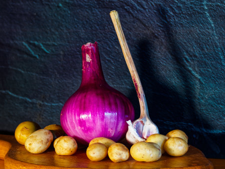 Purple onion and potatoes on a wooden table against a dark backgroundの写真素材