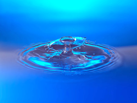 Water drop collision on a blue background. Splash effect after collision a falling drops with water...