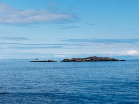 Lighthouse on a rock in the middle of the ocean, blue sky