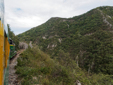 Passenger train passing through green mountains off Romania.の写真素材