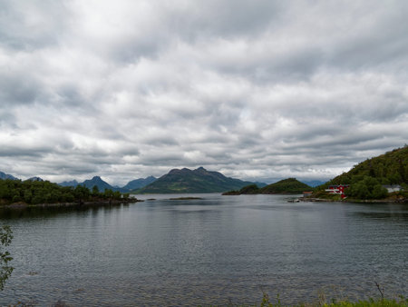 Norwegian fjord landscape with mountains and cloudy sky in summerの写真素材