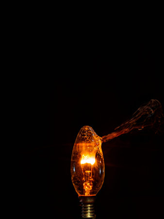 Incandescent light bulb with smoke on a black background. Close up.