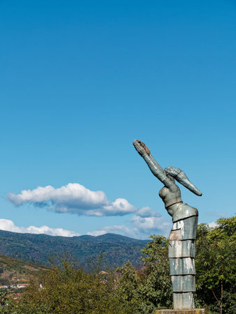 Statue of a girl on the background of the mountains and blue sky