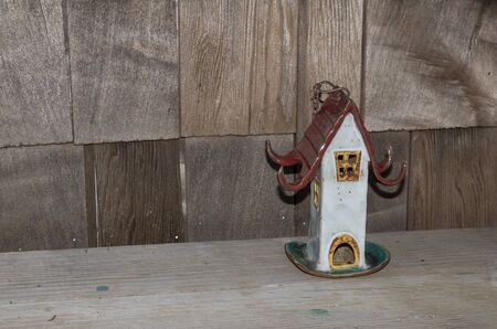 Ceramic pottery birdhouse on a rustic wooden benchの写真素材